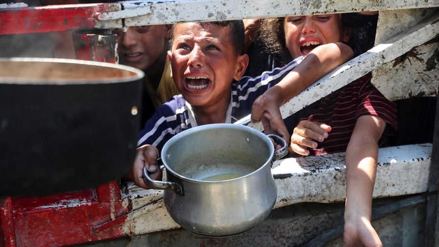 Palestinians wait to receive food from a charity kitchen, amid a hunger crisis, in Gaza City, July 23, 2025. REUTERS/Mahmoud Issa