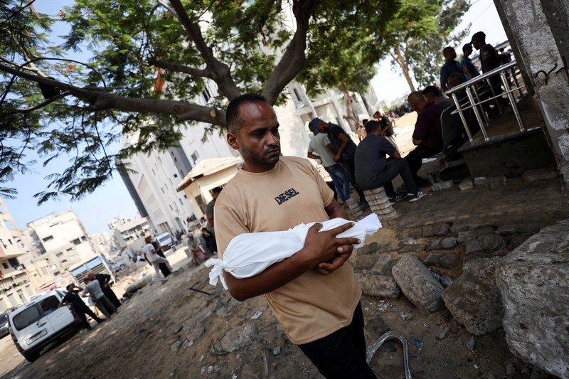 Palestinians wait to receive food from a charity kitchen, amid a hunger crisis, in Gaza City, July 23, 2025. REUTERS/Mahmoud Issa