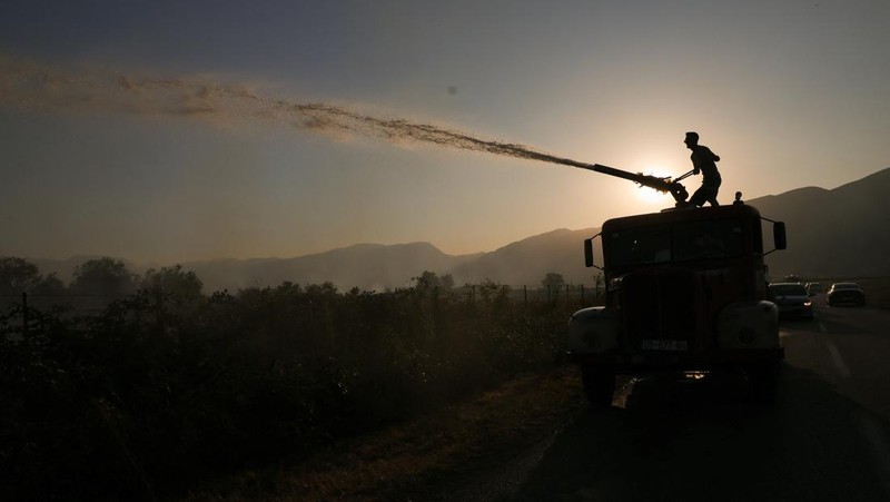 Seseorang berdiri di tengah asap saat kebakaran hutan melanda sebuah desa di Dubrava, Kosovo, 22 Juli 2025. (REUTERS/Valdrin Xhemaj)