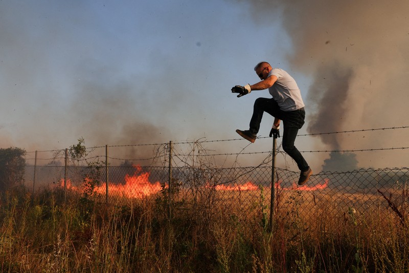 Seseorang berdiri di tengah asap saat kebakaran hutan melanda sebuah desa di Dubrava, Kosovo, 22 Juli 2025. Seseorang berdiri di tengah asap saat kebakaran hutan melanda sebuah desa di Dubrava, Kosovo, 22 Juli 2025. (REUTERS/Valdrin Xhemaj)