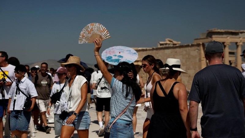 Orang-orang berjalan di depan kuil Erechtheion di puncak bukit Acropolis saat gelombang panas melanda dengan suhu diperkirakan mencapai 40 derajat Celsius, di Athena, Yunani, 24 Juli 2025. (REUTERS/Louiza Vradi)