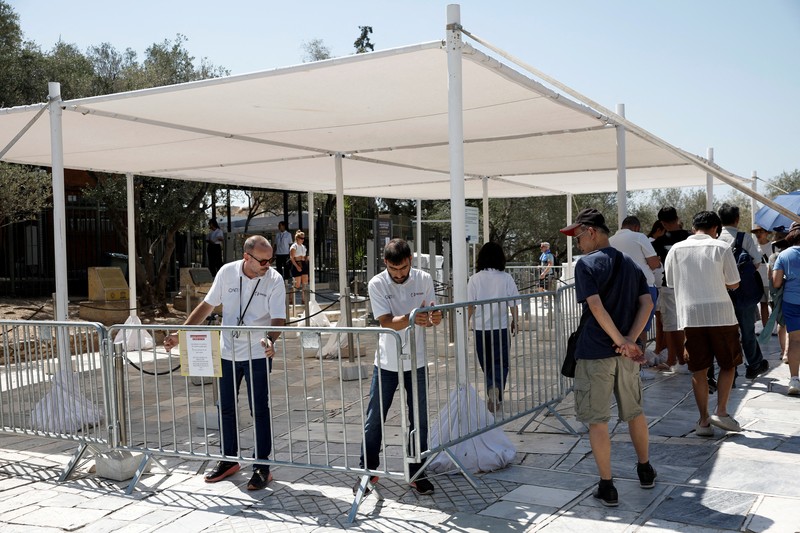 Orang-orang berjalan di depan kuil Erechtheion di puncak bukit Acropolis saat gelombang panas melanda dengan suhu diperkirakan mencapai 40 derajat Celsius, di Athena, Yunani, 24 Juli 2025. (REUTERS/Louiza Vradi)