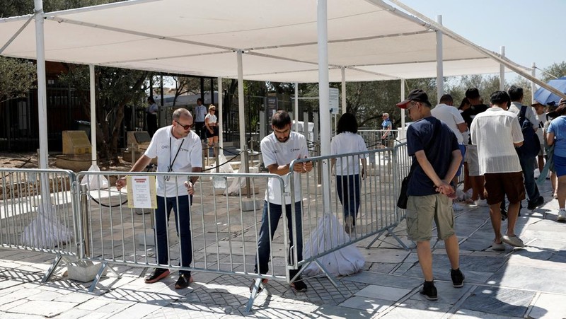Orang-orang berjalan di depan kuil Erechtheion di puncak bukit Acropolis saat gelombang panas melanda dengan suhu diperkirakan mencapai 40 derajat Celsius, di Athena, Yunani, 24 Juli 2025. (REUTERS/Louiza Vradi)