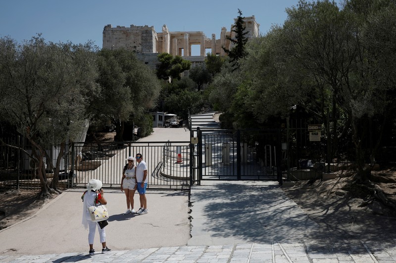 Orang-orang berjalan di depan kuil Erechtheion di puncak bukit Acropolis saat gelombang panas melanda dengan suhu diperkirakan mencapai 40 derajat Celsius, di Athena, Yunani, 24 Juli 2025. (REUTERS/Louiza Vradi)