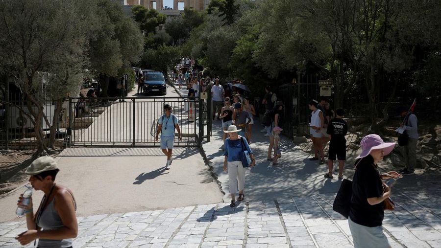 Orang-orang berjalan di depan kuil Erechtheion di puncak bukit Acropolis saat gelombang panas melanda dengan suhu diperkirakan mencapai 40 derajat Celsius, di Athena, Yunani, 24 Juli 2025. (REUTERS/Louiza Vradi)