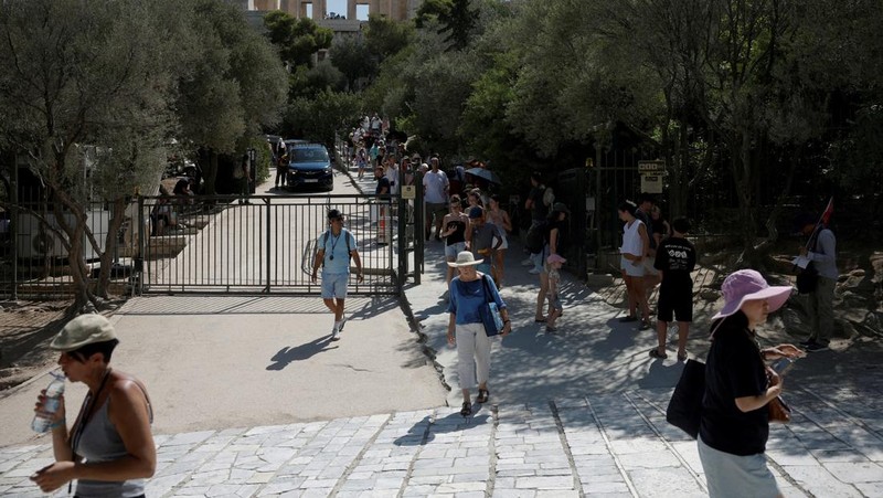 Orang-orang berjalan di depan kuil Erechtheion di puncak bukit Acropolis saat gelombang panas melanda dengan suhu diperkirakan mencapai 40 derajat Celsius, di Athena, Yunani, 24 Juli 2025. (REUTERS/Louiza Vradi)