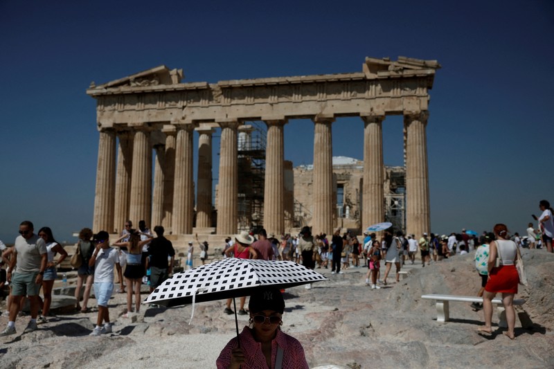 Orang-orang berjalan di depan kuil Erechtheion di puncak bukit Acropolis saat gelombang panas melanda dengan suhu diperkirakan mencapai 40 derajat Celsius, di Athena, Yunani, 24 Juli 2025. (REUTERS/Louiza Vradi)