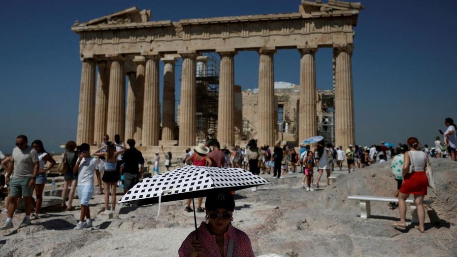 Orang-orang berjalan di depan kuil Erechtheion di puncak bukit Acropolis saat gelombang panas melanda dengan suhu diperkirakan mencapai 40 derajat Celsius, di Athena, Yunani, 24 Juli 2025. (REUTERS/Louiza Vradi)