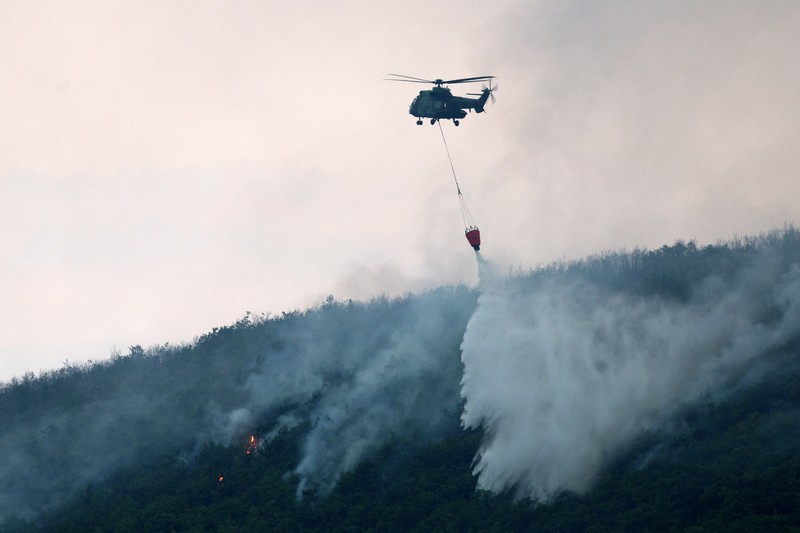 Seorang anggota layanan darurat berdiri di samping kebakaran hutan di dekat Bulqiza, Albania, Sabtu (26/7/2025). (REUTERS/Florion Goga) Seorang anggota layanan darurat berdiri di samping kebakaran hutan di dekat Bulqiza, Albania, Sabtu (26/7/2025). (REUTERS/Florion Goga)