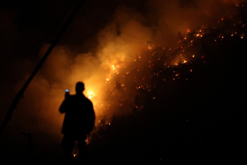 Seorang anggota layanan darurat berdiri di samping kebakaran hutan di dekat Bulqiza, Albania, Sabtu (26/7/2025). (REUTERS/Florion Goga) Seorang anggota layanan darurat berdiri di samping kebakaran hutan di dekat Bulqiza, Albania, Sabtu (26/7/2025). (REUTERS/Florion Goga)