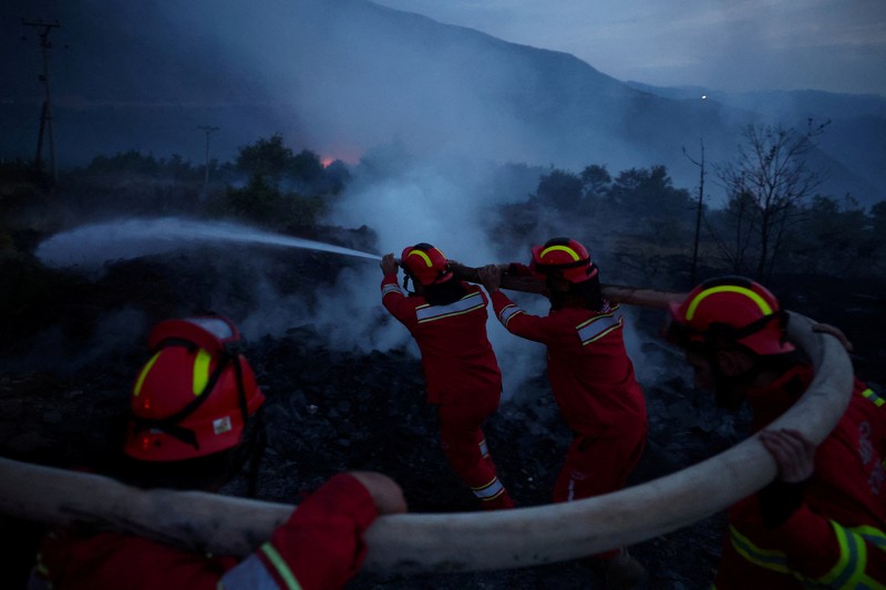 Seorang anggota layanan darurat berdiri di samping kebakaran hutan di dekat Bulqiza, Albania, Sabtu (26/7/2025). (REUTERS/Florion Goga) Seorang anggota layanan darurat berdiri di samping kebakaran hutan di dekat Bulqiza, Albania, Sabtu (26/7/2025). (REUTERS/Florion Goga)
