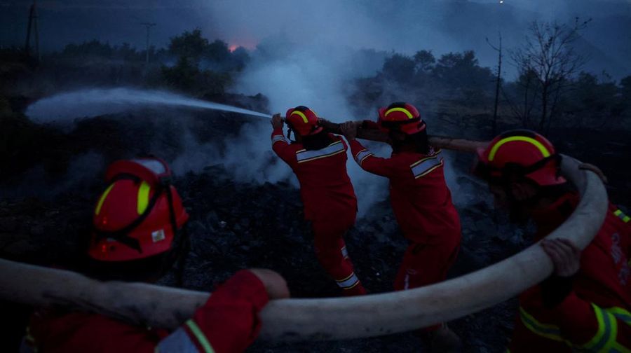 Seorang anggota layanan darurat berdiri di samping kebakaran hutan di dekat Bulqiza, Albania, Sabtu (26/7/2025). (REUTERS/Florion Goga)