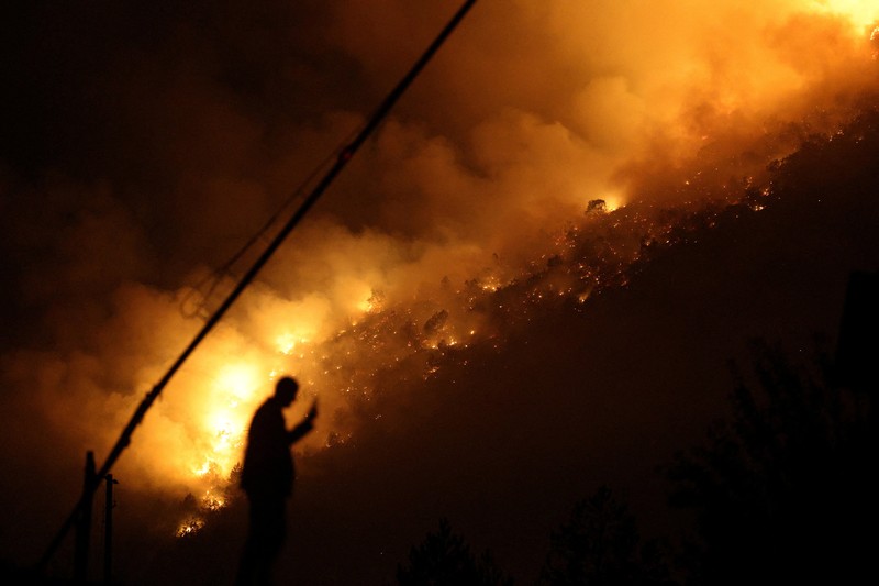 Seorang anggota layanan darurat berdiri di samping kebakaran hutan di dekat Bulqiza, Albania, Sabtu (26/7/2025). (REUTERS/Florion Goga) Seorang anggota layanan darurat berdiri di samping kebakaran hutan di dekat Bulqiza, Albania, Sabtu (26/7/2025). (REUTERS/Florion Goga)