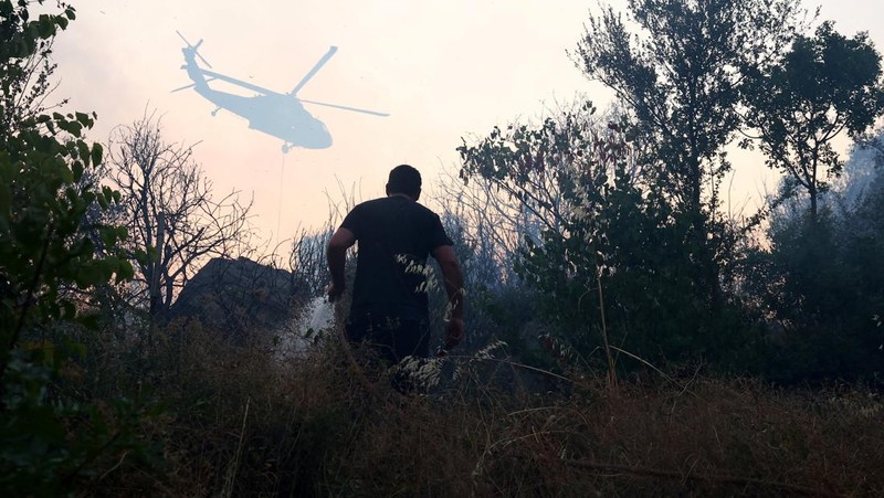 Anggota layanan darurat bekerja untuk memadamkan kebakaran hutan di Kalas, Delvina, Albania, 27 Juli 2025. (REUTERS/Florion Goga)