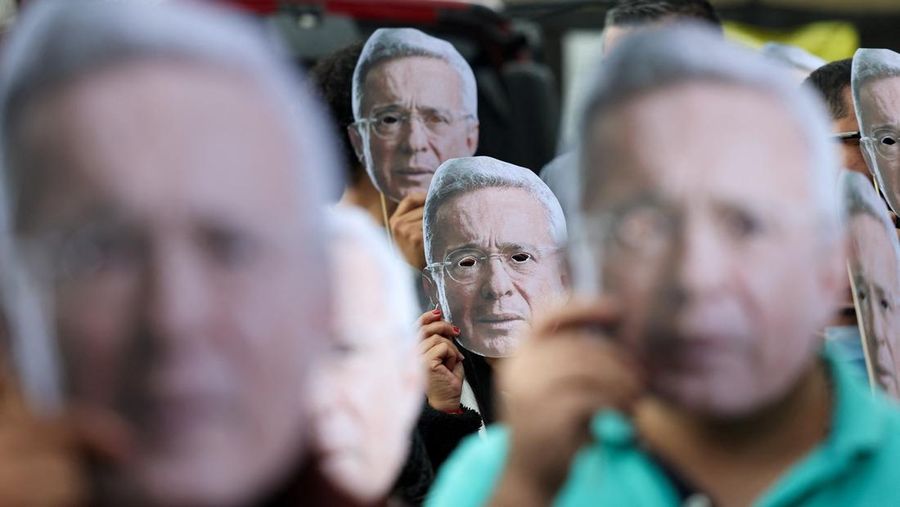 Orang-orang memegang topeng yang menggambarkan mantan Presiden Kolombia Alvaro Uribe, saat mereka berunjuk rasa untuk mendukung Uribe di luar kompleks pengadilan Paloquemao sambil menunggu putusan dalam kasus pidana terhadapnya, di Bogota, Kolombia, 28 Juli 2025. (REUTERS/Luisa Gonzalez)