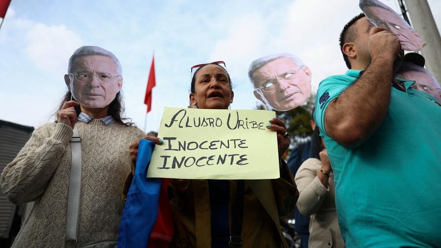 Orang-orang memegang topeng yang menggambarkan mantan Presiden Kolombia Alvaro Uribe, saat mereka berunjuk rasa untuk mendukung Uribe di luar kompleks pengadilan Paloquemao sambil menunggu putusan dalam kasus pidana terhadapnya, di Bogota, Kolombia, 28 Juli 2025. (REUTERS/Luisa Gonzalez)