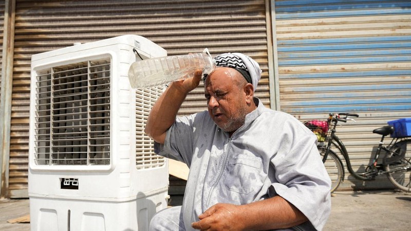 Seorang pria mendinginkan wajahnya dengan kabut air dari alat penyiram selama gelombang panas di Baghdad, Irak, 28 Juli 2025. (REUTERS/Ahmed Saad)