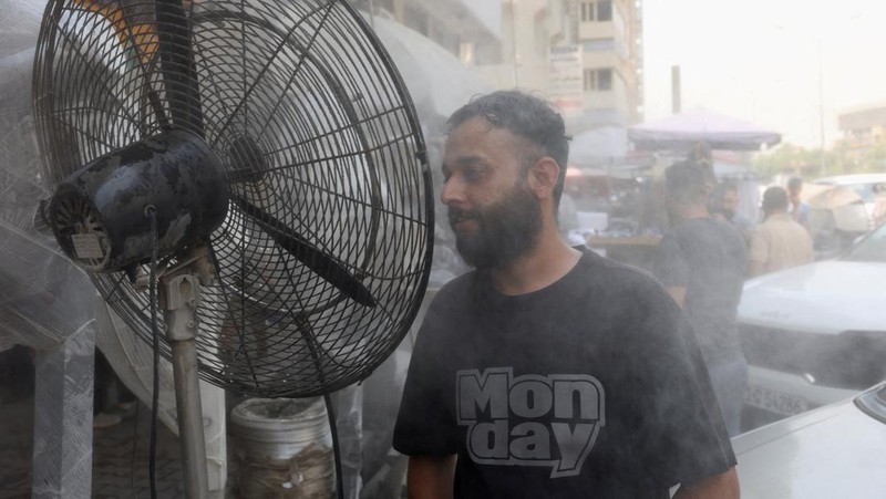 Seorang pria mendinginkan wajahnya dengan kabut air dari alat penyiram selama gelombang panas di Baghdad, Irak, 28 Juli 2025. (REUTERS/Ahmed Saad)