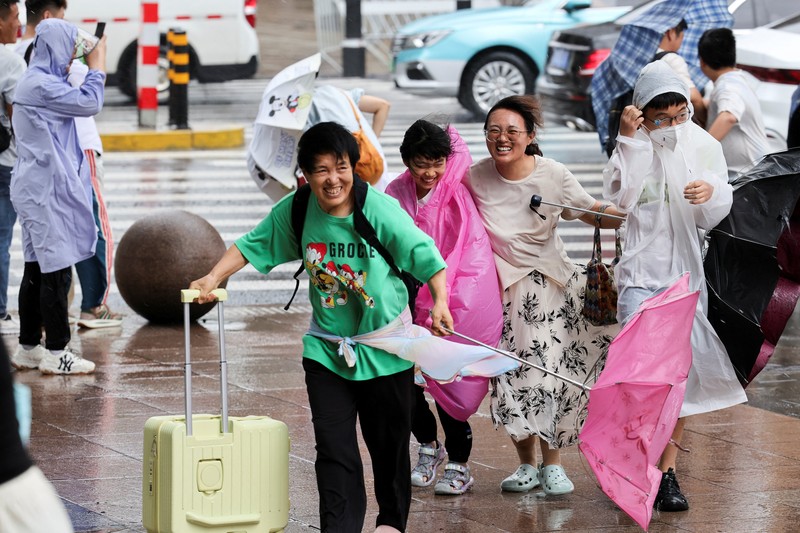 Orang-orang mencoba memperbaiki payung yang tertiup angin saat berjalan di jalan saat hujan deras dan angin kencang, setelah Badai Tropis Co-May mendarat di kota terdekat, di Shanghai, CHina, Rabu (30/7/2025). (REUTERS/Go Nakamura) Orang-orang mencoba memperbaiki payung yang tertiup angin saat berjalan di jalan saat hujan deras dan angin kencang, setelah Badai Tropis Co-May mendarat di kota terdekat, di Shanghai, CHina, Rabu (30/7/2025). (REUTERS/Go Nakamura)