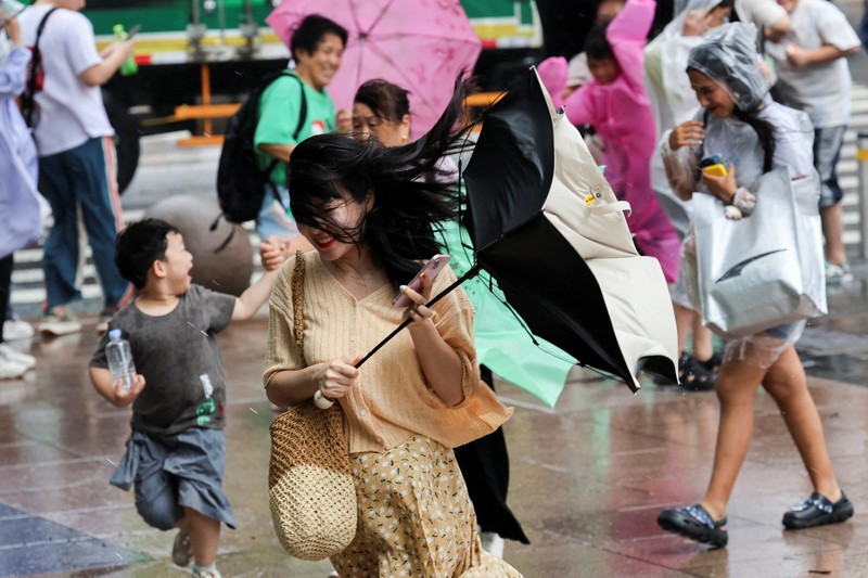 Orang-orang mencoba memperbaiki payung yang tertiup angin saat berjalan di jalan saat hujan deras dan angin kencang, setelah Badai Tropis Co-May mendarat di kota terdekat, di Shanghai, CHina, Rabu (30/7/2025). (REUTERS/Go Nakamura) Orang-orang mencoba memperbaiki payung yang tertiup angin saat berjalan di jalan saat hujan deras dan angin kencang, setelah Badai Tropis Co-May mendarat di kota terdekat, di Shanghai, CHina, Rabu (30/7/2025). (REUTERS/Go Nakamura)