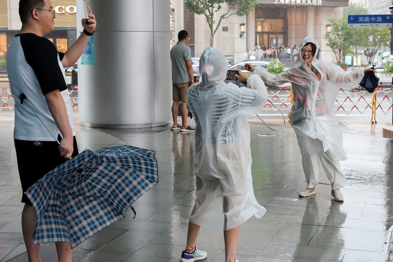Orang-orang mencoba memperbaiki payung yang tertiup angin saat berjalan di jalan saat hujan deras dan angin kencang, setelah Badai Tropis Co-May mendarat di kota terdekat, di Shanghai, CHina, Rabu (30/7/2025). (REUTERS/Go Nakamura) Orang-orang mencoba memperbaiki payung yang tertiup angin saat berjalan di jalan saat hujan deras dan angin kencang, setelah Badai Tropis Co-May mendarat di kota terdekat, di Shanghai, CHina, Rabu (30/7/2025). (REUTERS/Go Nakamura)