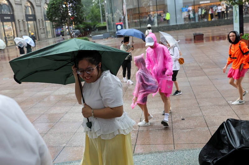 Orang-orang mencoba memperbaiki payung yang tertiup angin saat berjalan di jalan saat hujan deras dan angin kencang, setelah Badai Tropis Co-May mendarat di kota terdekat, di Shanghai, CHina, Rabu (30/7/2025). (REUTERS/Go Nakamura) Orang-orang mencoba memperbaiki payung yang tertiup angin saat berjalan di jalan saat hujan deras dan angin kencang, setelah Badai Tropis Co-May mendarat di kota terdekat, di Shanghai, CHina, Rabu (30/7/2025). (REUTERS/Go Nakamura)