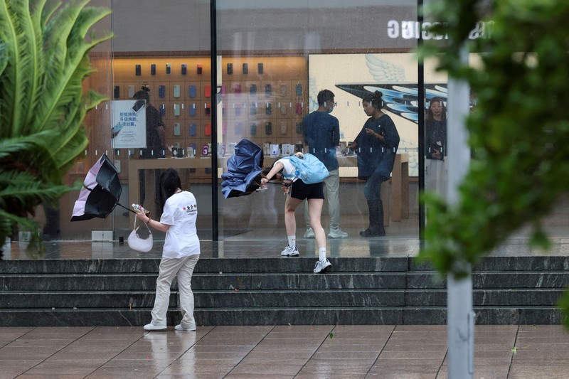 Orang-orang mencoba memperbaiki payung yang tertiup angin saat berjalan di jalan saat hujan deras dan angin kencang, setelah Badai Tropis Co-May mendarat di kota terdekat, di Shanghai, CHina, Rabu (30/7/2025). (REUTERS/Go Nakamura) Orang-orang mencoba memperbaiki payung yang tertiup angin saat berjalan di jalan saat hujan deras dan angin kencang, setelah Badai Tropis Co-May mendarat di kota terdekat, di Shanghai, CHina, Rabu (30/7/2025). (REUTERS/Go Nakamura)