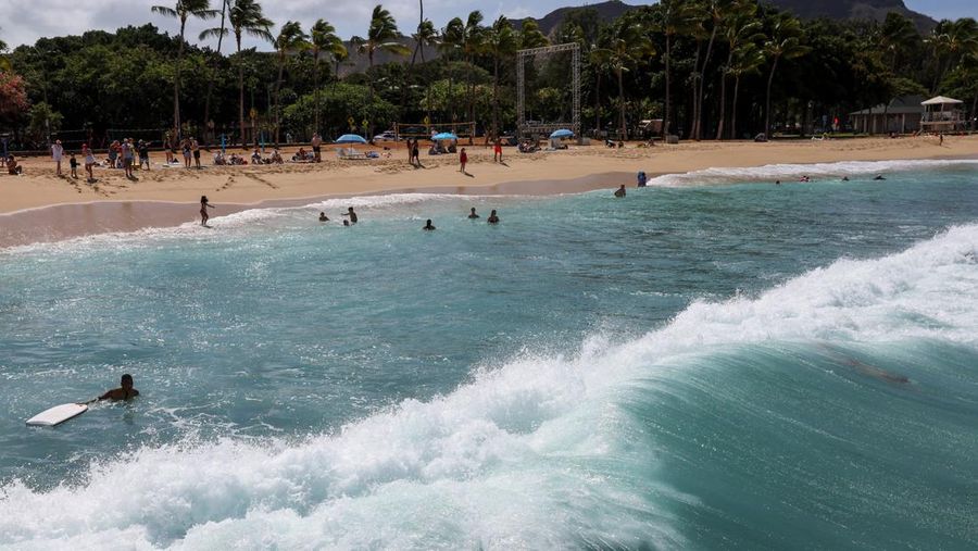 Saat sepasang kekasih berjalan di pantai, ombak menghantam Pantai Waikiki setelah pihak berwenang menurunkan peringatan tsunami sebelumnya menyusul gempa bumi di Semenanjung Kamchatka Timur Jauh Rusia, di Honolulu, Hawaii, AS, 30 Juli 2025. (REUTERS/Marco Garcia)
