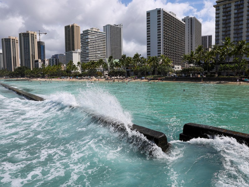 Saat sepasang kekasih berjalan di pantai, ombak menghantam Pantai Waikiki setelah pihak berwenang menurunkan peringatan tsunami sebelumnya menyusul gempa bumi di Semenanjung Kamchatka Timur Jauh Rusia, di Honolulu, Hawaii, AS, 30 Juli 2025. (REUTERS/Marco Garcia)