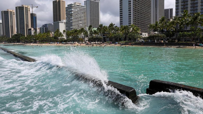 Saat sepasang kekasih berjalan di pantai, ombak menghantam Pantai Waikiki setelah pihak berwenang menurunkan peringatan tsunami sebelumnya menyusul gempa bumi di Semenanjung Kamchatka Timur Jauh Rusia, di Honolulu, Hawaii, AS, 30 Juli 2025. (REUTERS/Marco Garcia)