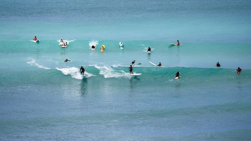 Saat sepasang kekasih berjalan di pantai, ombak menghantam Pantai Waikiki setelah pihak berwenang menurunkan peringatan tsunami sebelumnya menyusul gempa bumi di Semenanjung Kamchatka Timur Jauh Rusia, di Honolulu, Hawaii, AS, 30 Juli 2025. (REUTERS/Marco Garcia)