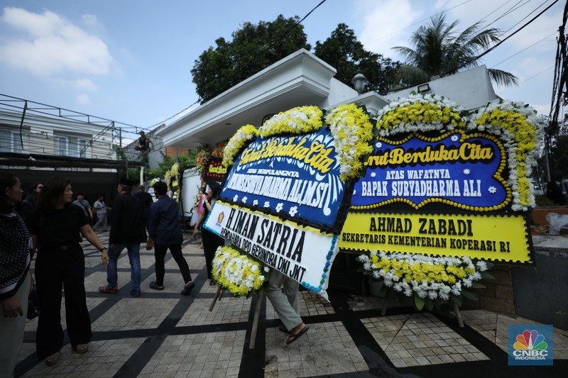Petugas menata karangan bunga di kediaman almarhum Suryadharma Ali di Jl. Cipinang Cempedak I No.30, Cipinang Cempedak, Kecamatan Jatinegara, Kota Jakarta Timur, Kamis (31/7/2025). (CNBC Indonesia/Tri Susilo)