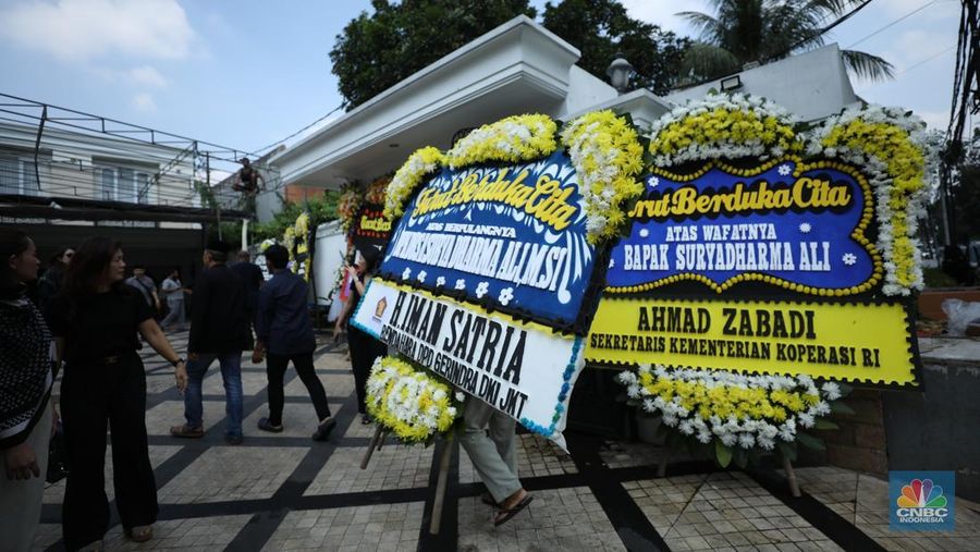 Petugas menata karangan bunga di kediaman almarhum Suryadharma Ali di Jl. Cipinang Cempedak I No.30, Cipinang Cempedak, Kecamatan Jatinegara, Kota Jakarta Timur, Kamis (31/7/2025). (CNBC Indonesia/Tri Susilo)