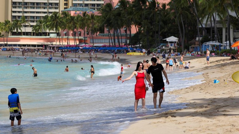 Saat sepasang kekasih berjalan di pantai, ombak menghantam Pantai Waikiki setelah pihak berwenang menurunkan peringatan tsunami sebelumnya menyusul gempa bumi di Semenanjung Kamchatka Timur Jauh Rusia, di Honolulu, Hawaii, AS, 30 Juli 2025. (REUTERS/Marco Garcia)
