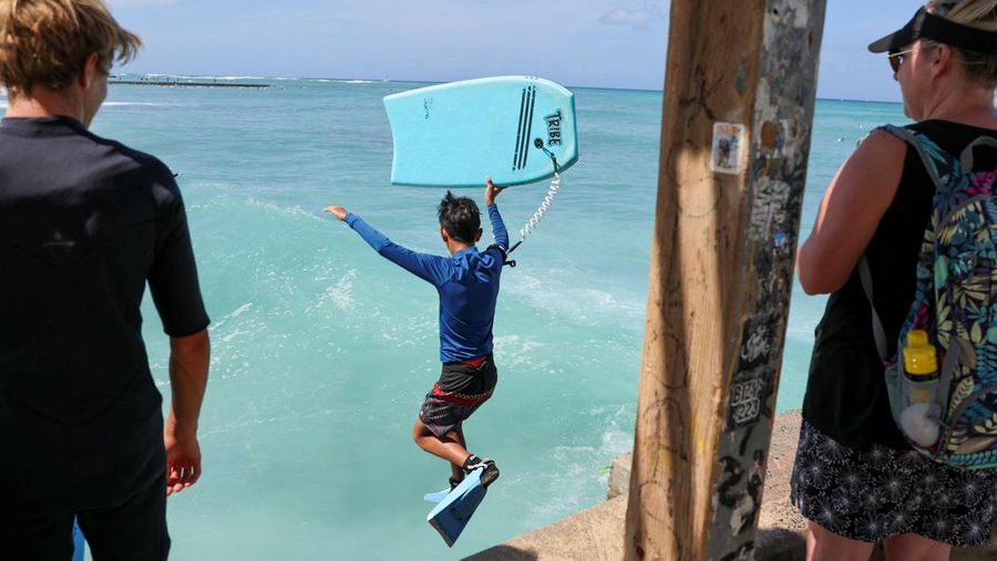 Saat sepasang kekasih berjalan di pantai, ombak menghantam Pantai Waikiki setelah pihak berwenang menurunkan peringatan tsunami sebelumnya menyusul gempa bumi di Semenanjung Kamchatka Timur Jauh Rusia, di Honolulu, Hawaii, AS, 30 Juli 2025. (REUTERS/Marco Garcia)