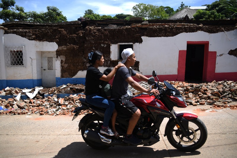 Seorang wanita dan seorang anak berjalan di samping puing-puing bangunan yang rusak setelah gempa bumi, di Comapa, Jutiapa, Guatemala, 30 Juli 2025. (REUTERS/Cristina Chiquin)