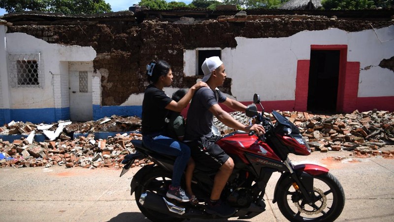 Seorang wanita dan seorang anak berjalan di samping puing-puing bangunan yang rusak setelah gempa bumi, di Comapa, Jutiapa, Guatemala, 30 Juli 2025. (REUTERS/Cristina Chiquin)