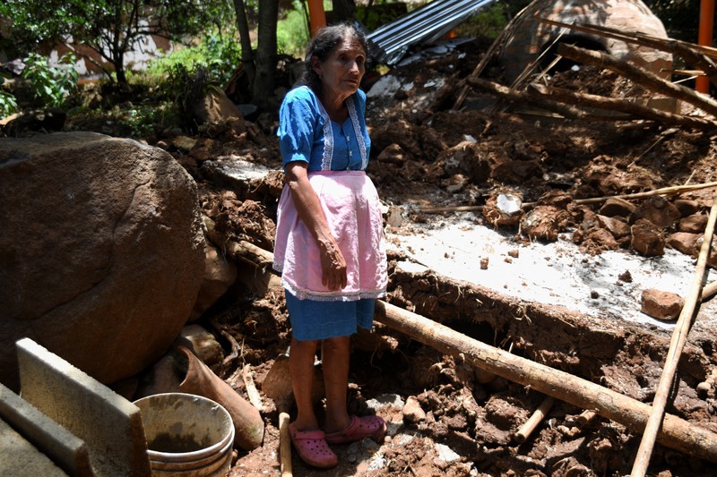 Seorang wanita dan seorang anak berjalan di samping puing-puing bangunan yang rusak setelah gempa bumi, di Comapa, Jutiapa, Guatemala, 30 Juli 2025. (REUTERS/Cristina Chiquin)