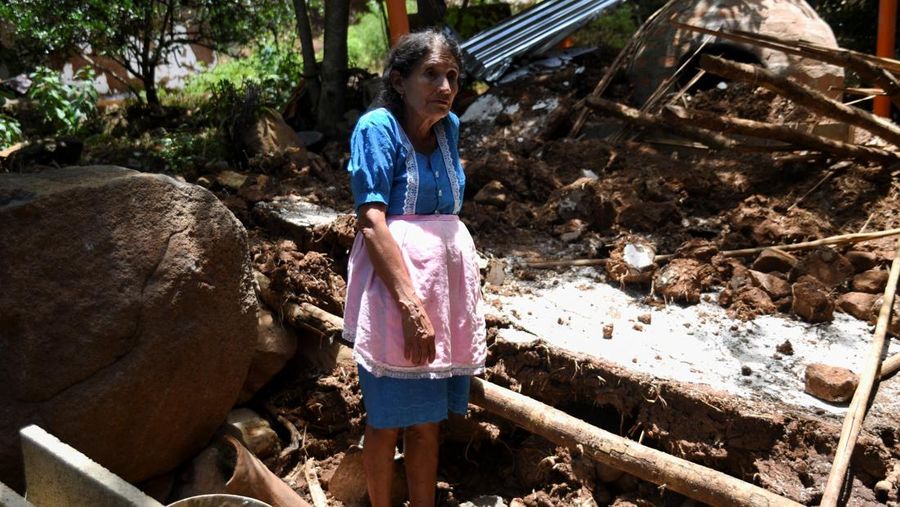 Seorang wanita dan seorang anak berjalan di samping puing-puing bangunan yang rusak setelah gempa bumi, di Comapa, Jutiapa, Guatemala, 30 Juli 2025. (REUTERS/Cristina Chiquin)