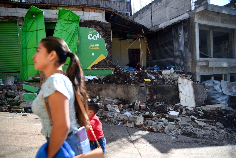 Seorang wanita dan seorang anak berjalan di samping puing-puing bangunan yang rusak setelah gempa bumi, di Comapa, Jutiapa, Guatemala, 30 Juli 2025. (REUTERS/Cristina Chiquin)