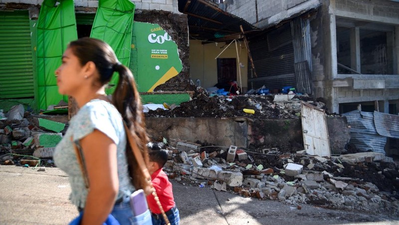 Seorang wanita dan seorang anak berjalan di samping puing-puing bangunan yang rusak setelah gempa bumi, di Comapa, Jutiapa, Guatemala, 30 Juli 2025. (REUTERS/Cristina Chiquin)