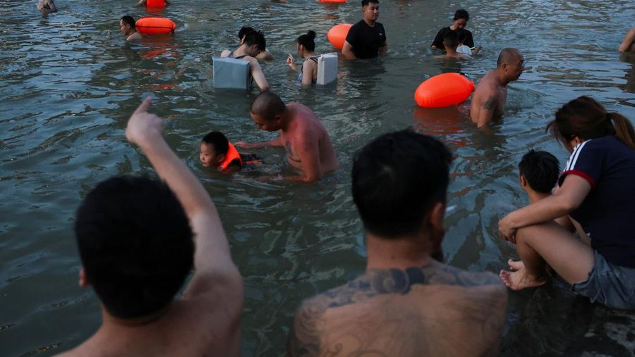 Seorang anak membilas wajahnya dengan air dari pancuran untuk menyejukkan diri di tengah peringatan bahaya panas di Chongqing, Tiongkok, 31 Juli 2025. (REUTERS/Go Nakamura)