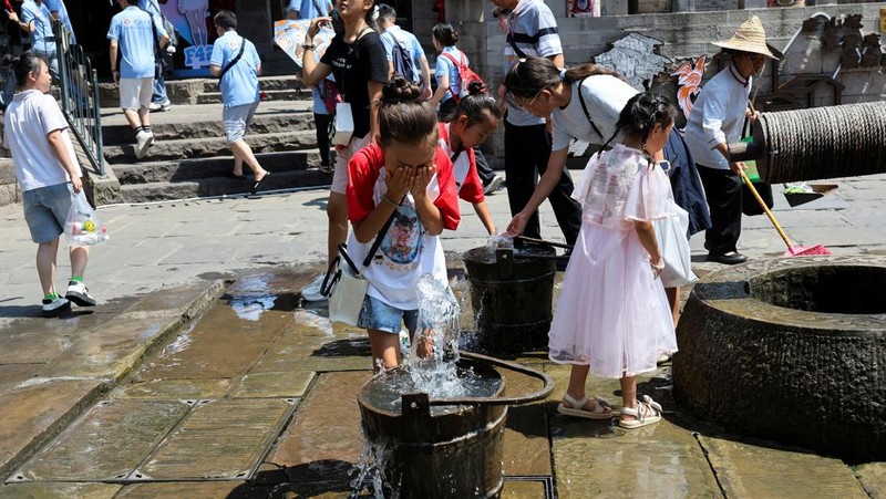 Seorang anak membilas wajahnya dengan air dari pancuran untuk menyejukkan diri di tengah peringatan bahaya panas di Chongqing, Tiongkok, 31 Juli 2025. (REUTERS/Go Nakamura)