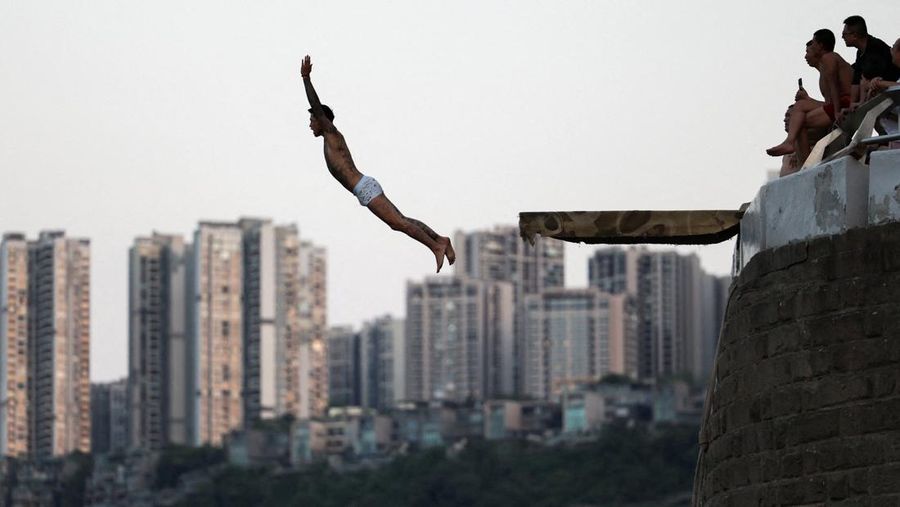 Seseorang melompat dari papan loncat ke Sungai Jialing di tengah peringatan merah suhu panas di Chongqing, Cina, 31 Juli 2025. (REUTERS/Go Nakamura)