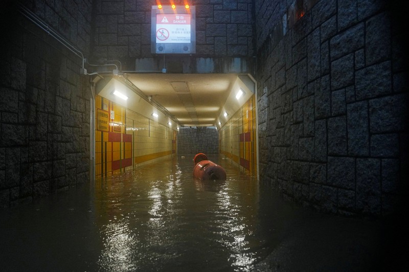 Banjir saat hujan deras di Hong Kong, Selasa (5/8/2025). Pejalan kaki berjalan melewati area yang terendam banjir saat hujan deras di Hong Kong, Selasa (5/8/2025). (REUTERS/Lam Yik)