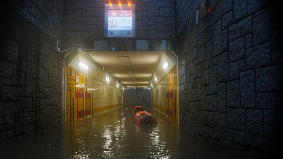 Pejalan kaki berjalan melewati area yang terendam banjir saat hujan deras di Hong Kong, Selasa (5/8/2025). (REUTERS/Lam Yik)