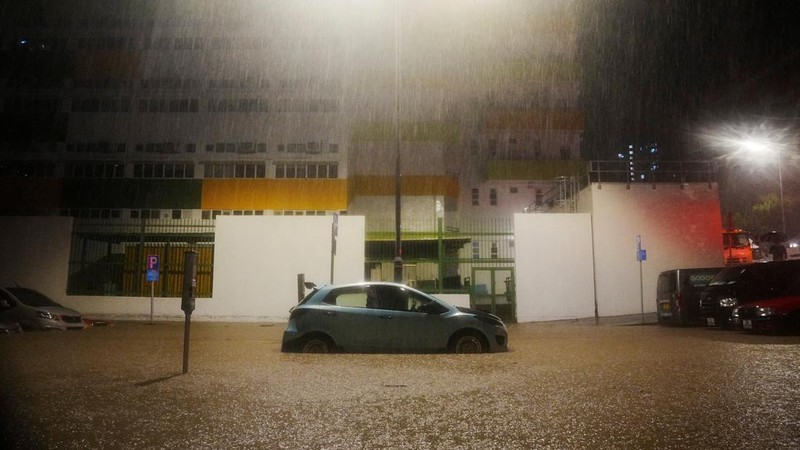 Pejalan kaki berjalan melewati area yang terendam banjir saat hujan deras di Hong Kong, Selasa (5/8/2025). (REUTERS/Lam Yik)