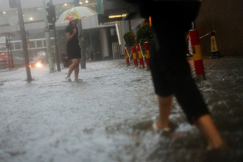 Banjir saat hujan deras di Hong Kong, Selasa (5/8/2025). Pejalan kaki berjalan melewati area yang terendam banjir saat hujan deras di Hong Kong, Selasa (5/8/2025). (REUTERS/Lam Yik)