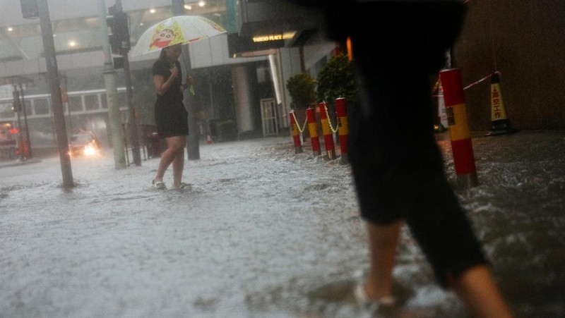 Pejalan kaki berjalan melewati area yang terendam banjir saat hujan deras di Hong Kong, Selasa (5/8/2025). (REUTERS/Lam Yik)