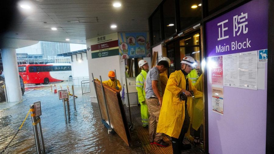 Pejalan kaki berjalan melewati area yang terendam banjir saat hujan deras di Hong Kong, Selasa (5/8/2025). (REUTERS/Lam Yik)